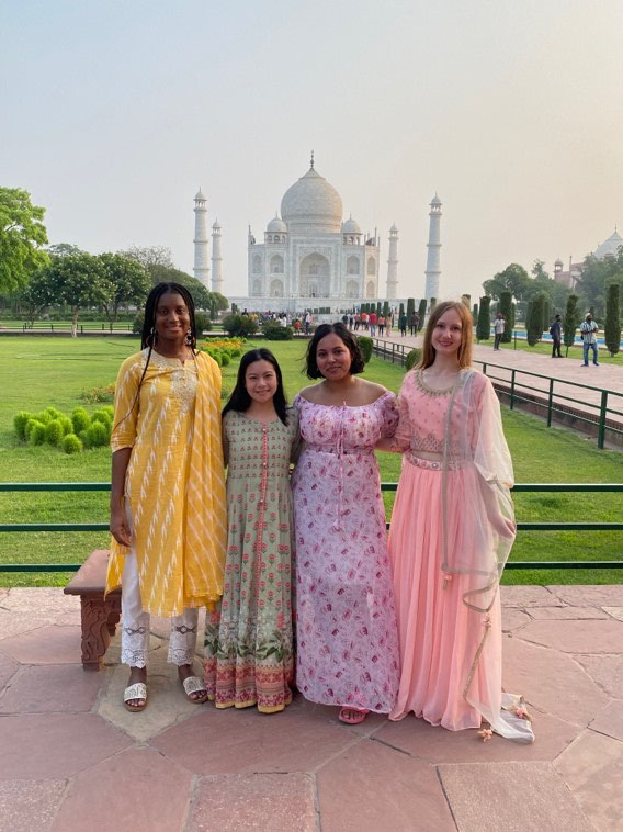 Group of four students standing in front of the Taj Mahal