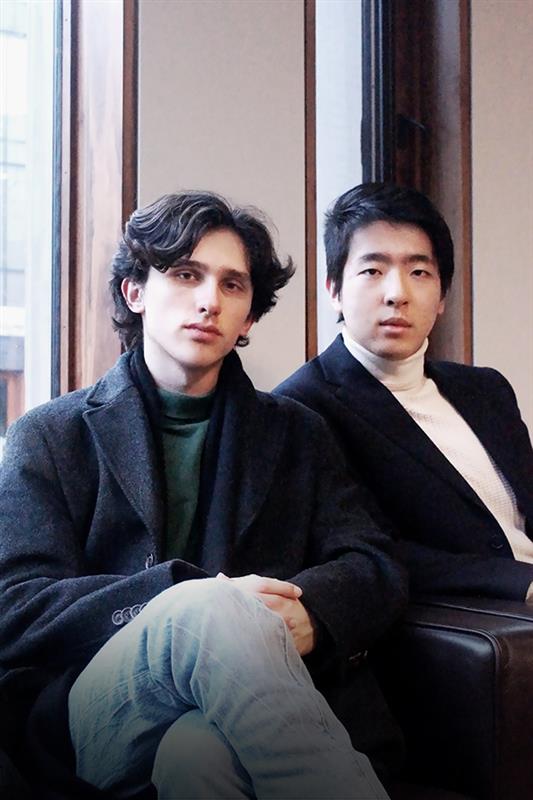 Ben and nick staring at the camera by a window at the Ivey building