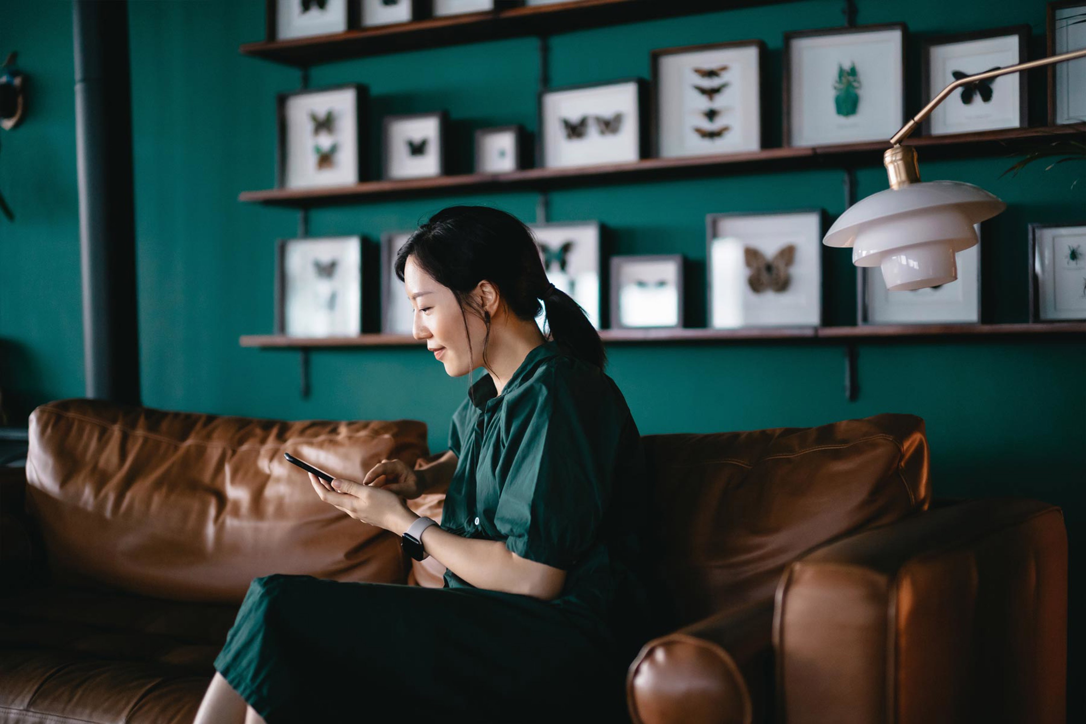 A Woman Sitting On A Couch Browsing On A Mobile Device