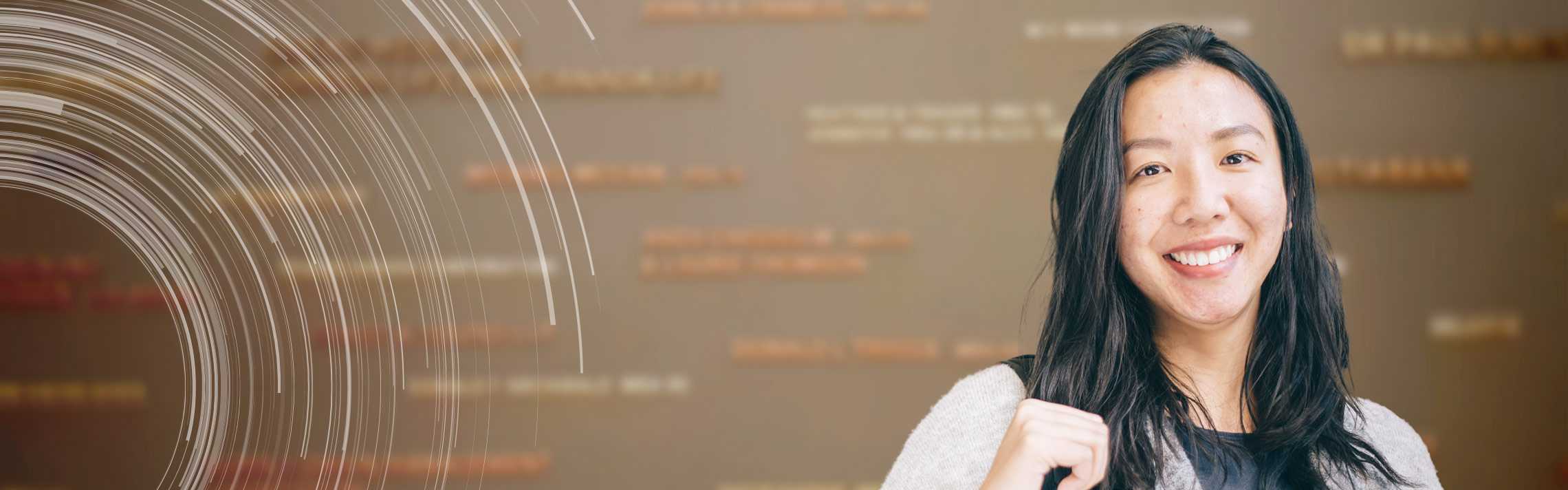 Portrait of smiling university student standing in front of donor names on a wall.